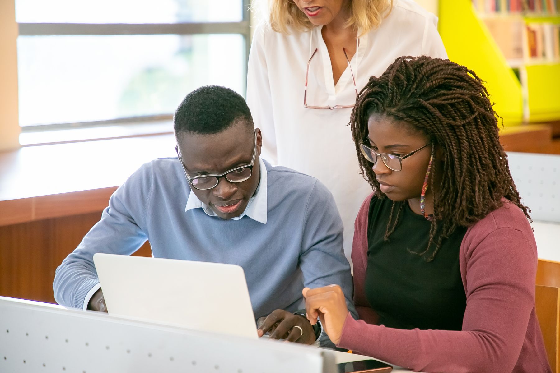 Students collaborating around a laptop in a library